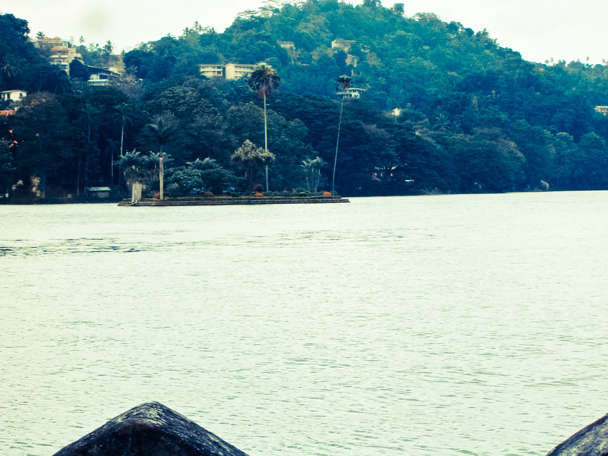 Kandy Lake viewed from the hills above, mist rolling over the surrounding peaks at dawn