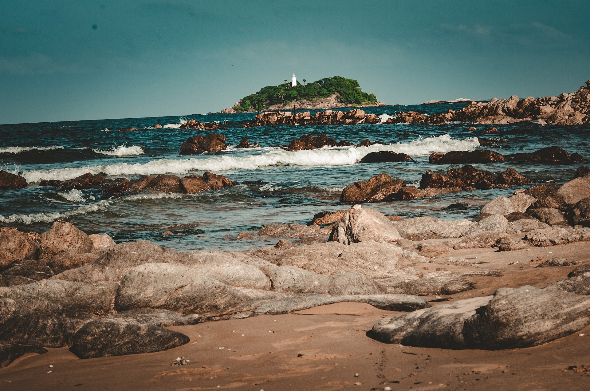 A calm, dry-season beach on Sri Lanka's east coast with clear turquoise water — where travellers should point for sun at the late-September to early-October weather seam