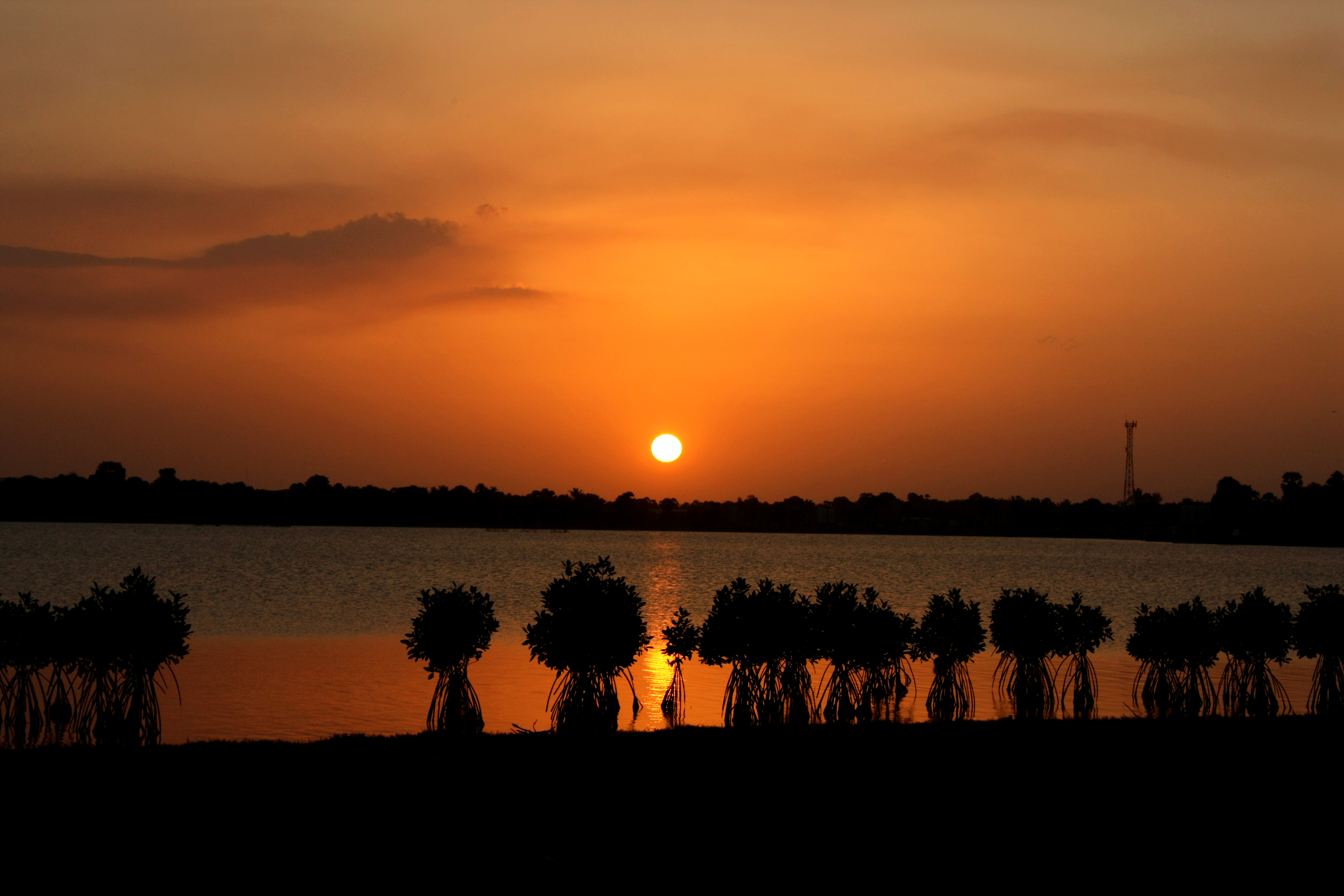 Batticaloa Lagoon at sunset with calm waters reflecting orange and pink sky