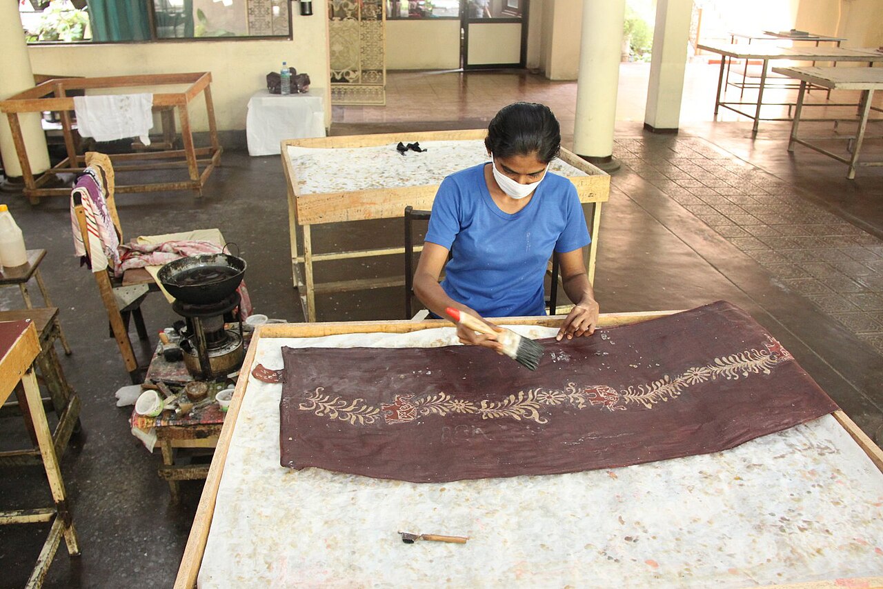 A batik painter applying wax and dye by hand at a Sri Lankan craft workshop