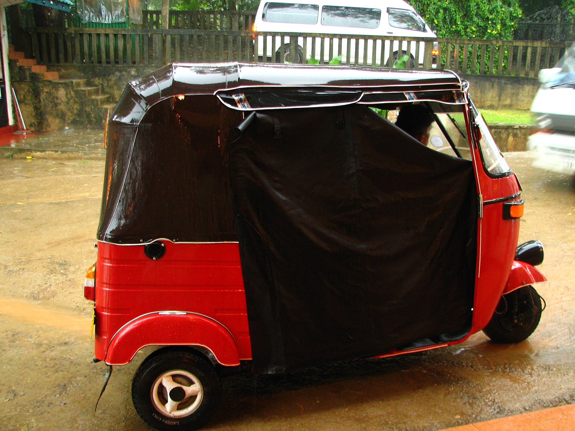A yellow tuk-tuk parked on a Sri Lankan street, preparing for rain — the island’s most common way to get around